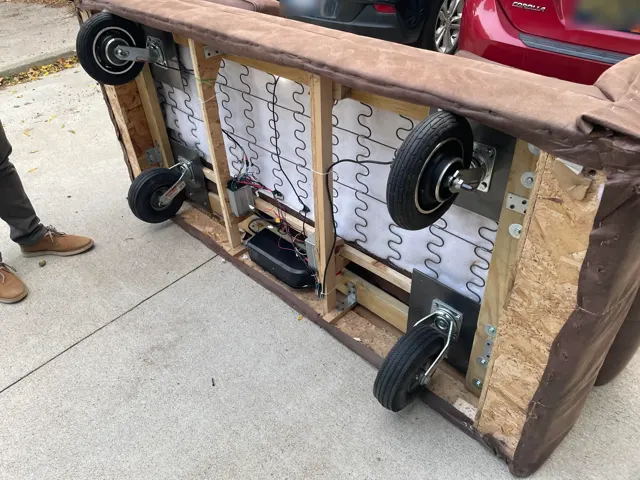 Underside of the couch: two hub-motor wheels, two casters, motor controllers and a battery between the frame rails